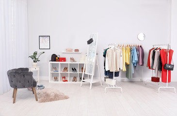Light room interior with stylish clothes and shoes