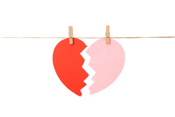 Halves of paper heart hanging on rope against white background. Relationship problems