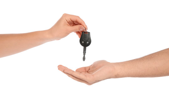 Agent giving car key to man on white background, closeup. Getting driving license