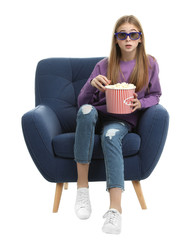 Emotional teenage girl with 3D glasses and popcorn sitting in armchair during cinema show on white background