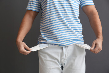 Man showing empty pockets on grey background, closeup