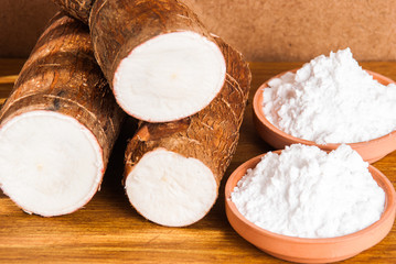 Raw cassava tuber on wooden background - Manihot esculenta