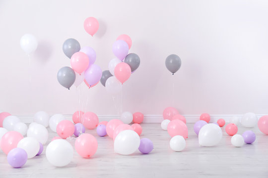 Room decorated with colorful balloons near wall