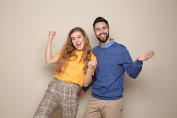Fototapeta premium Happy young people celebrating victory on color background