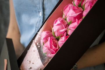 Florist's work: A girl demonstrates a box with a bouquet of pink roses.