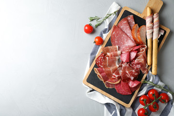 Different meat delicacies served on gray table, top view. Space for text