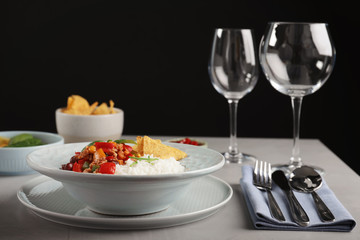 Tasty chili con carne served with rice on gray table. Dinner in restaurant
