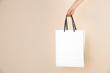 Woman holding paper shopping bag on color background. Mock up for design