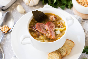 Thick pea soup with smoked meats in a white plate