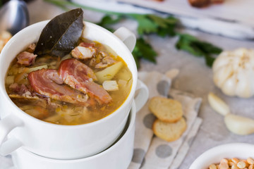 Thick pea soup with smoked meats in a white plate
