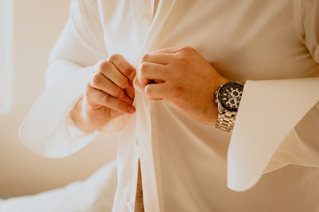 Groom buttoning a button