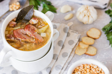 Thick pea soup with smoked meats in a white plate