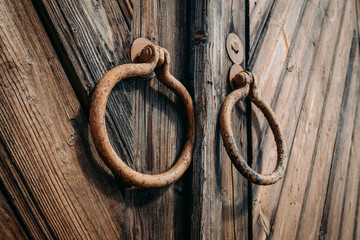 Round metal handles on closed old antique wooden gate or door