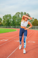 Woman on running track has side cramps during workout