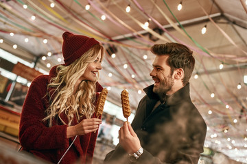 Happy couple at street fair. Young couple look at vegan sausage in dough