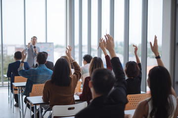 Raised up hands and arms of large group in seminar class room to agree with speaker at conference...