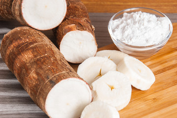 Raw cassava tuber on wooden background - Manihot esculenta