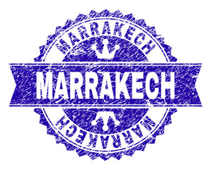 MARRAKECH rosette stamp seal watermark with grunge effect. Designed with round rosette, ribbon and small crowns. Blue vector rubber watermark of MARRAKECH text with grunge style.