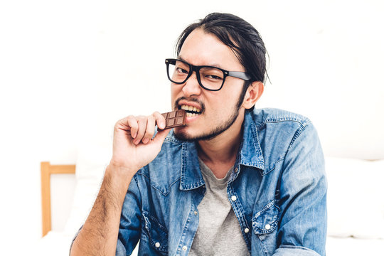 Young Man Enjoy Eating Chocolate Donut Cake At Home.unhealthy And Junk Food Concept