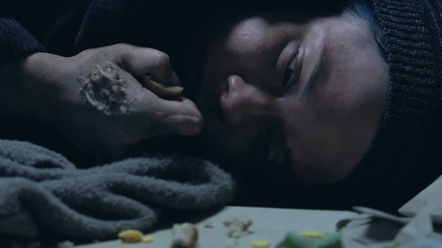 Sick homeless woman eating bread, starving and suffering infections, rotten skin