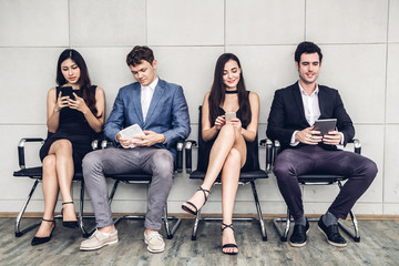 Group of business sitting relax use technology together of smartphone and tablet computer checking social apps and working on wall background.Communication concept