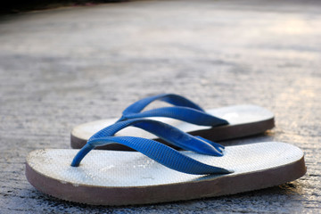 Close up used white and blue rubber slippers on an old concert.