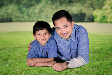 Little boy lying with his father in the park