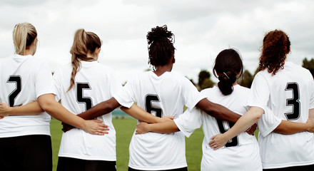 Fototapeta premium Female soccer players huddling and standing together
