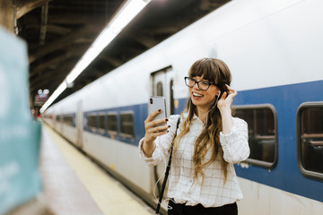 Cheerful woman having a video call at a subway platform