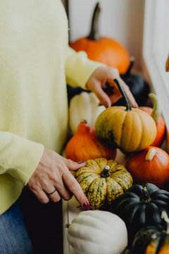 Woman decorating her house with pumpkins and squashes