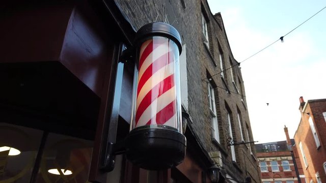 Spinning red and white barbers pole outside a barbershop