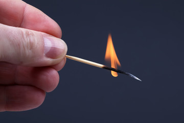 burning wooden match on dark background