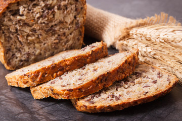 Loaf of wholegrain bread for breakfast and ears of rye or wheat grain