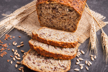 Loaf of wholegrain bread for breakfast, ingredients for baking and ears of rye or wheat grain
