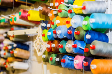 Spools of colorful Thread in sewing Studio.Selective focus.Colorful embroidery thread spool using in garment industry, row of multicolored yarn rolls, sewing material.