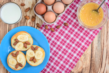 Pancakes with banana,nuts and honey on white plate for breakfast on wooden background with copy space.