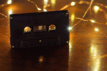 A black analog cassette tape on a wood table with soft lights.
