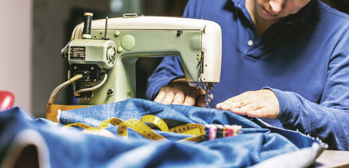 Sewing denim jeans with sewing machine. Repair jeans by sewing machine. Alteration jeans, hemming a pair of jeans, handmade garment industrial concept.