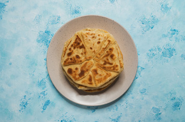 Moldovan Placinta on a plate on a blue table.