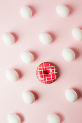 White eggs and pink donut on a light pink background with reflection of the shadows and copy space. layout to easter. Flat lay, pattern