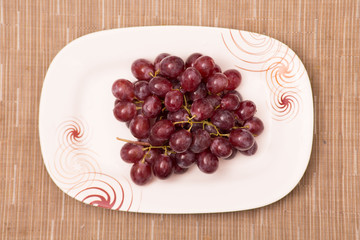 Red grapes on a plate and table set fresh and wet and sweet juicily delicious displayed 