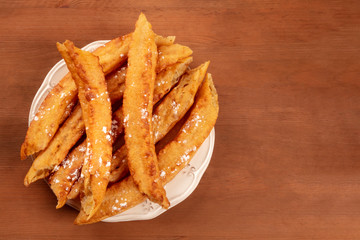 Traditional Spanish porras, a typical Madrid Sunday breakfast, shot from above on a dark rustic wooden background with a place for text