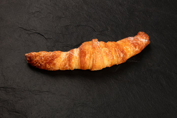 A croissant on a black background with copy space