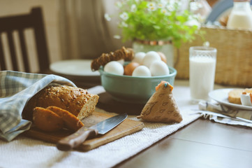 country breakfast on rustic home kitchen with farm eggs, butter, wholegrain bread and milk. Organic homemade food, easter concept.