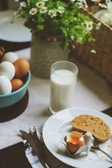 country breakfast on rustic home kitchen with farm eggs, butter, wholegrain bread and milk. Organic homemade food, easter concept.