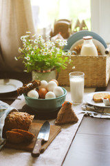country breakfast on rustic home kitchen with farm eggs, butter, wholegrain bread and milk. Organic...