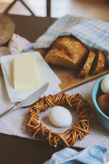 country breakfast on rustic home kitchen with farm eggs, butter, wholegrain bread and milk. Organic homemade food, easter concept.