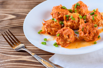 Stuffed cabbage in tomato sauce with green onion on wooden background.