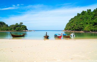 beautiful scenery with wood boat on the beach white sand in blue sea and blue sky on tropical beach .