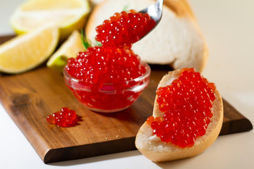red caviar in glassware on wooden background with space for text